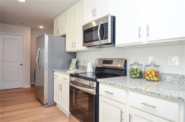 a kitchen with granite countertop stainless steel appliances a stove a microwave and cabinets