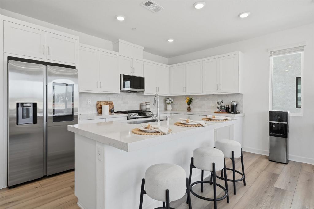 2402 Cascalote Loop San Diego, CA 92154 - Photo 5 of 35 a kitchen with stainless steel appliances a refrigerator stove microwave and cabinets