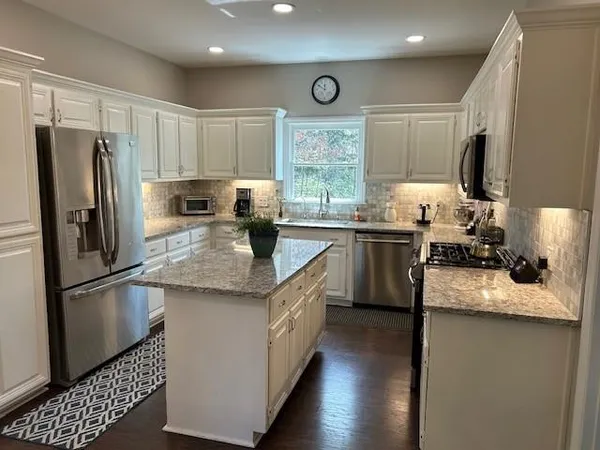 a kitchen with granite countertop stainless steel appliances a sink stove refrigerator and a window