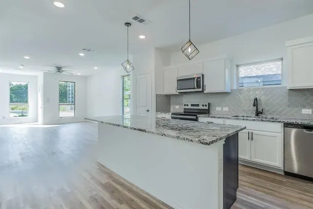 a kitchen with stainless steel appliances granite countertop a sink stove and a granite counter top
