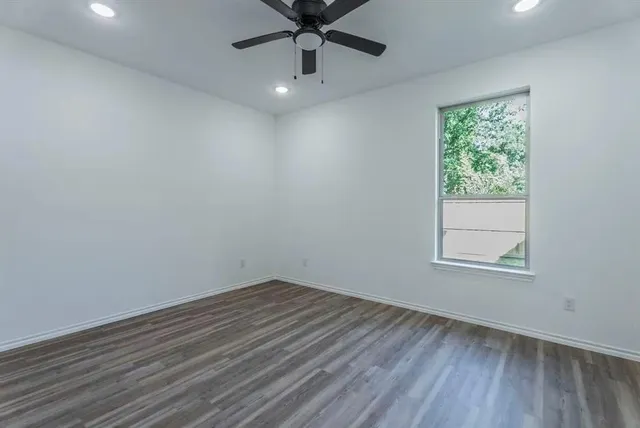 an empty room with a window and a ceiling fan