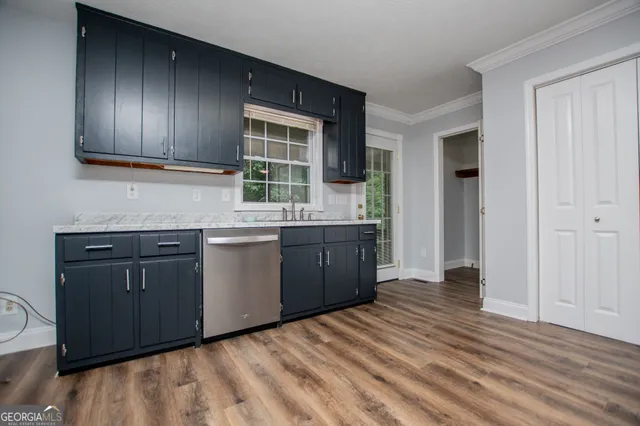a view of an empty room with wooden floor and a ceiling fan