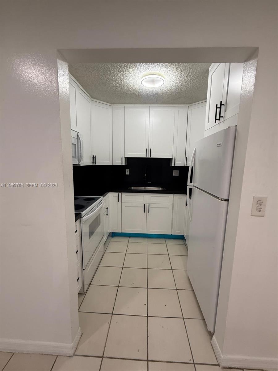 9520 Southwest 8th Street, Unit 111 Miami, FL 33174 - Photo 15 of 31 a kitchen with a sink a refrigerator and cabinets