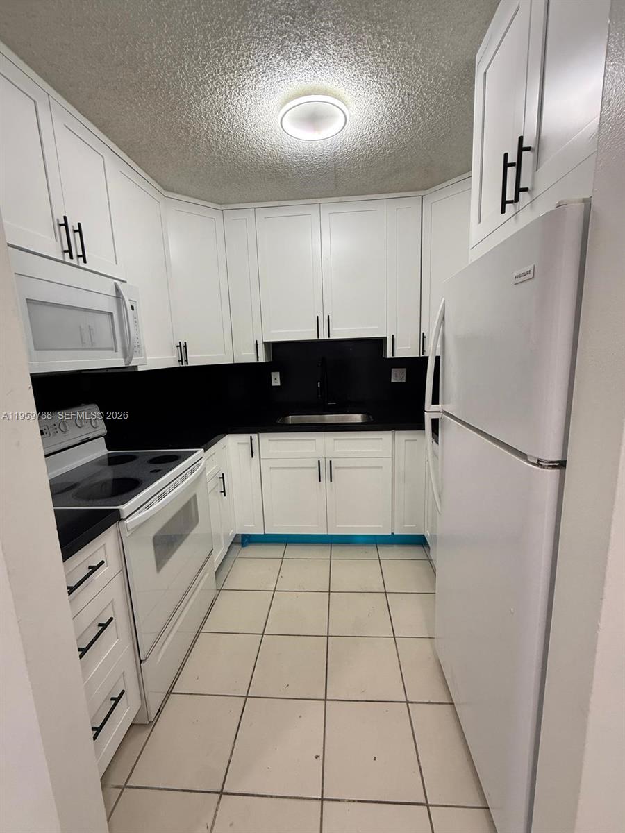 9520 Southwest 8th Street, Unit 111 Miami, FL 33174 - Photo 29 of 31 a kitchen with a sink a cabinetry and a refrigerator