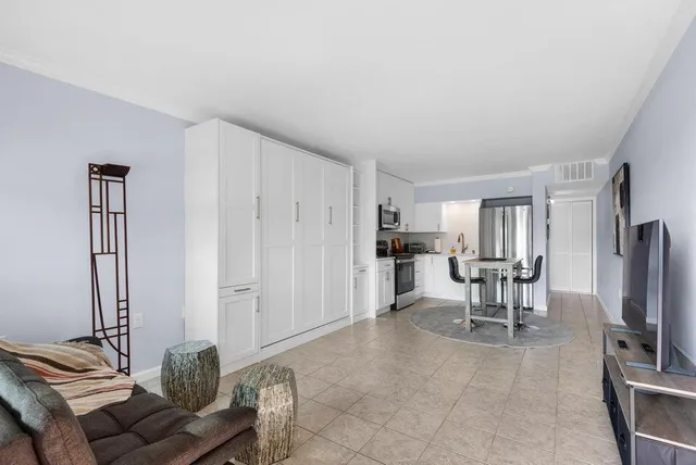 a living room with furniture a flat screen tv and a refrigerator