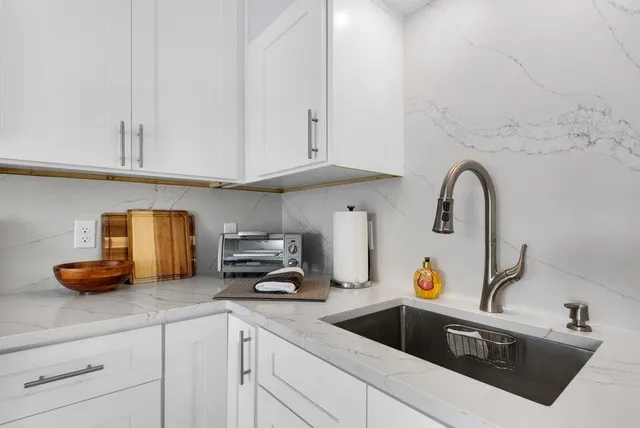 a kitchen with white cabinets and sink