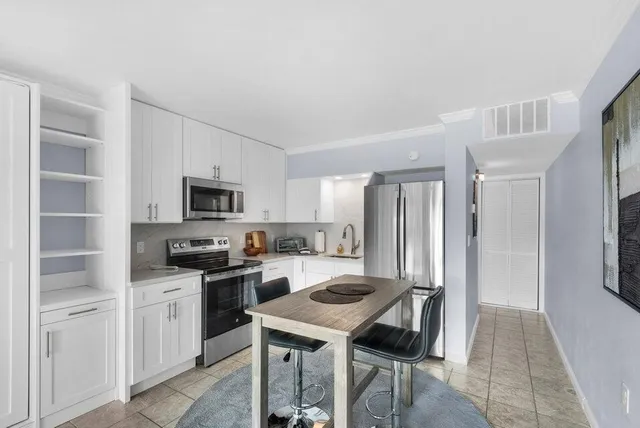 a kitchen with stainless steel appliances granite countertop a refrigerator a stove a sink dishwasher and white cabinets with wooden floor