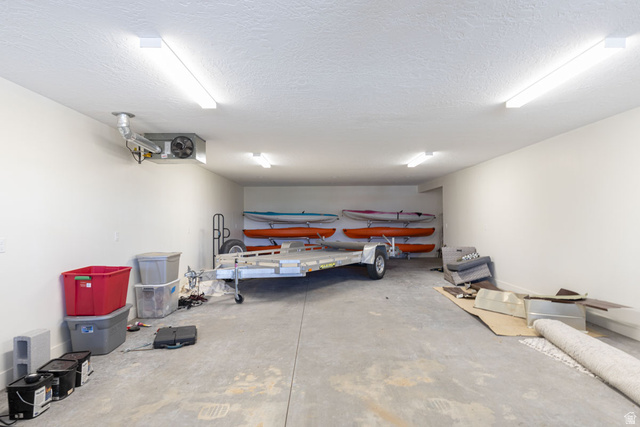 382 Ridgeview Street, Unit 8 & 9 Brian Head, UT 84719 - Photo 49 of 52 Spacious garage featuring a concrete floor, multiple ceiling-mounted fluorescent lights, white painted walls, and an exposed ventilation unit