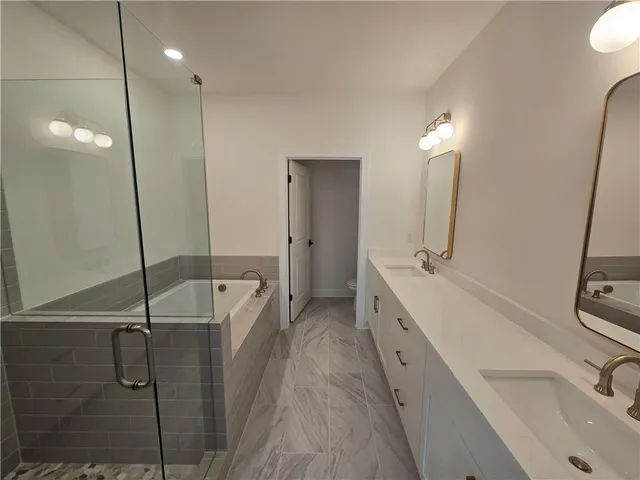 a bathroom with a double vanity sink a toilet and shower