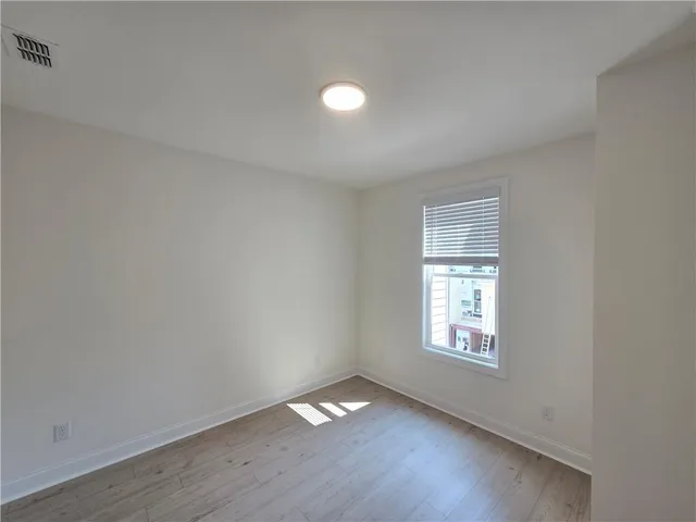 a view of an empty room with wooden floor and closet