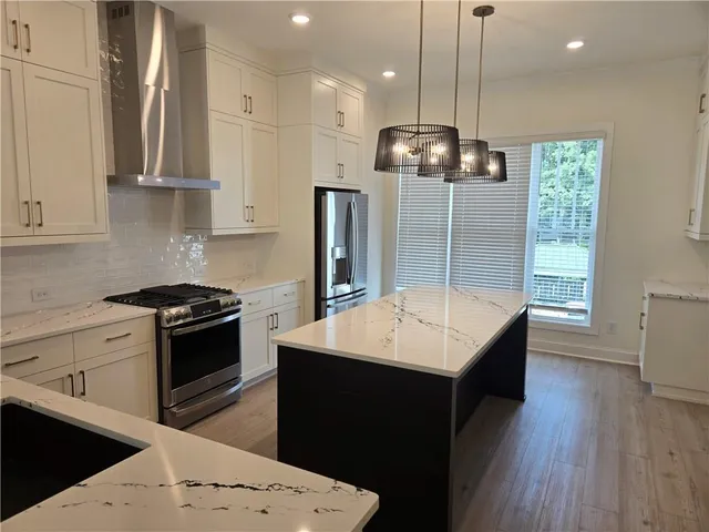 a kitchen with stainless steel appliances kitchen island a wooden floor and a view of living room