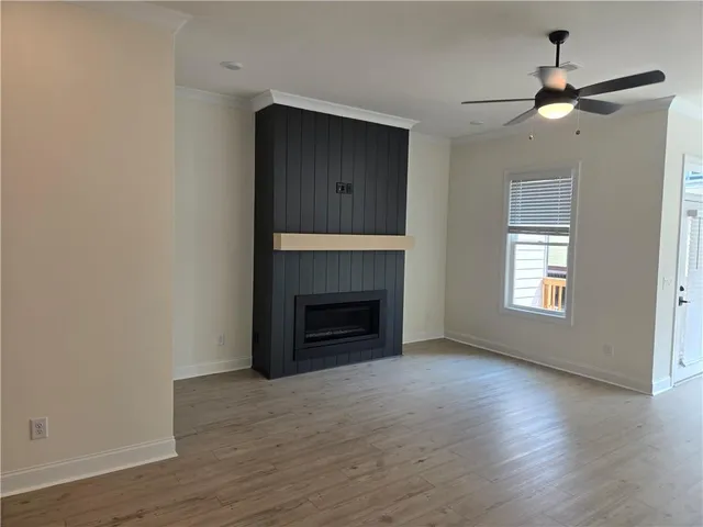 a view of an empty room with wooden floor fireplace and a window