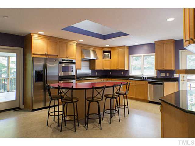 3105 Churchill Road Raleigh, NC 27607 - Photo 3 of 16 a kitchen with stainless steel appliances kitchen island granite countertop a table chairs and a refrigerator