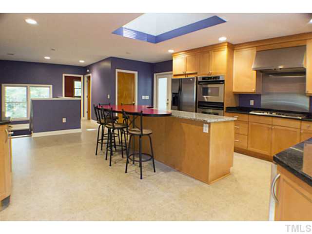 3105 Churchill Road Raleigh, NC 27607 - Photo 4 of 16 a kitchen with stainless steel appliances granite countertop a stove top oven a sink a dining table and chairs with wooden floor