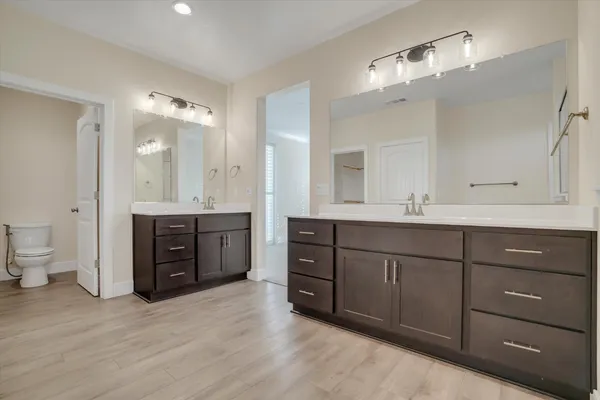 a bathroom with a granite countertop double vanity sink mirror and a toilet