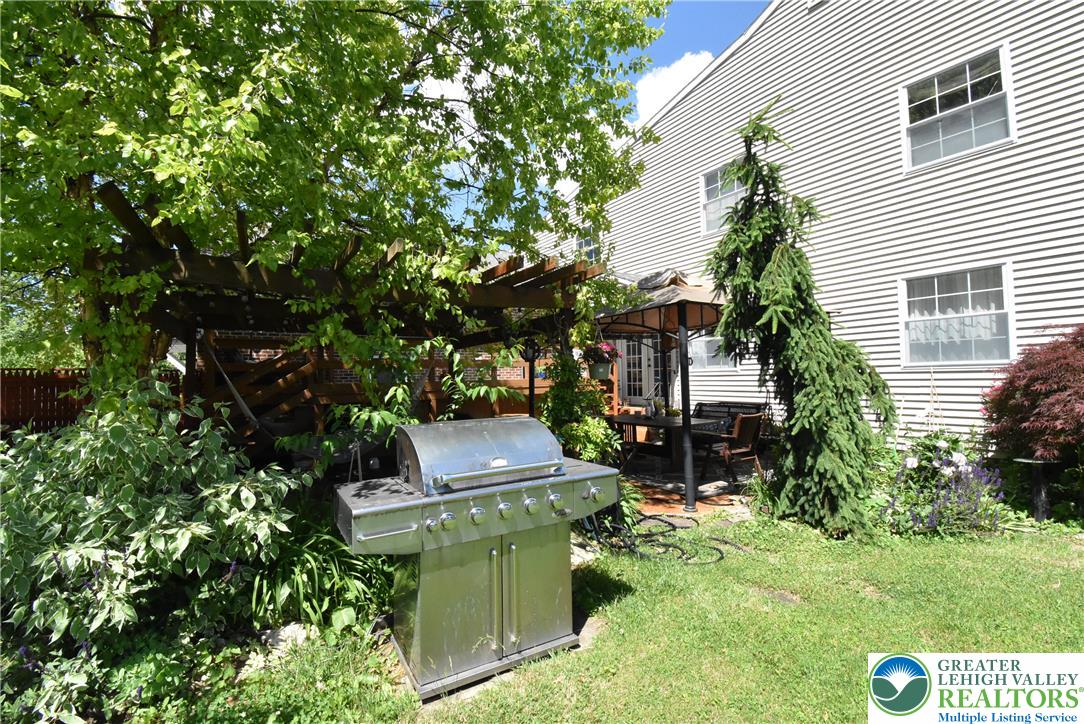 424 Grape Street Whitehall, PA 18052 - Photo 56 of 56 A verdant backyard retreat features a wooden pergola, lush landscaping, and a well-appointed patio.