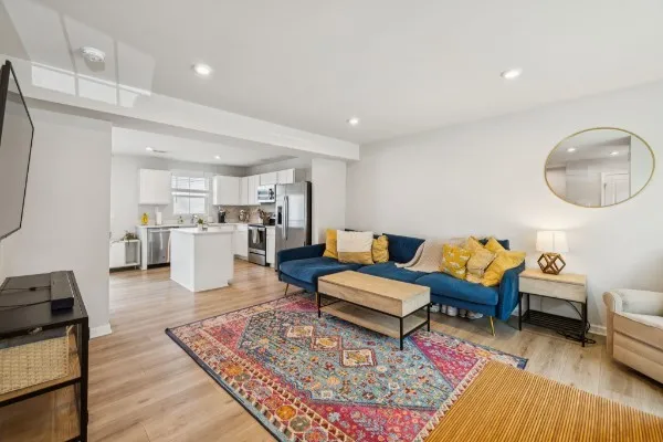 a living room with furniture couches and a dining table with wooden floor