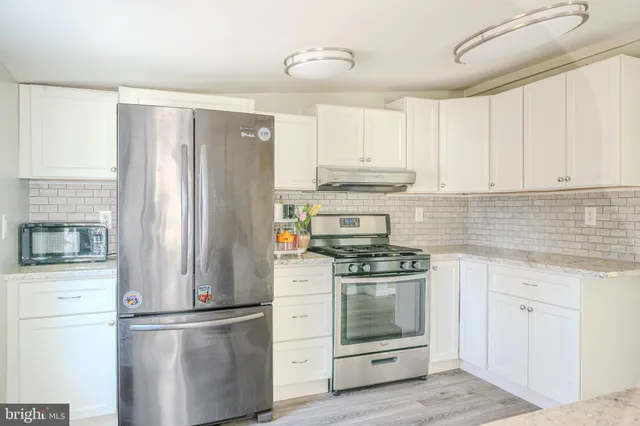 a kitchen with stainless steel appliances white cabinets and a refrigerator