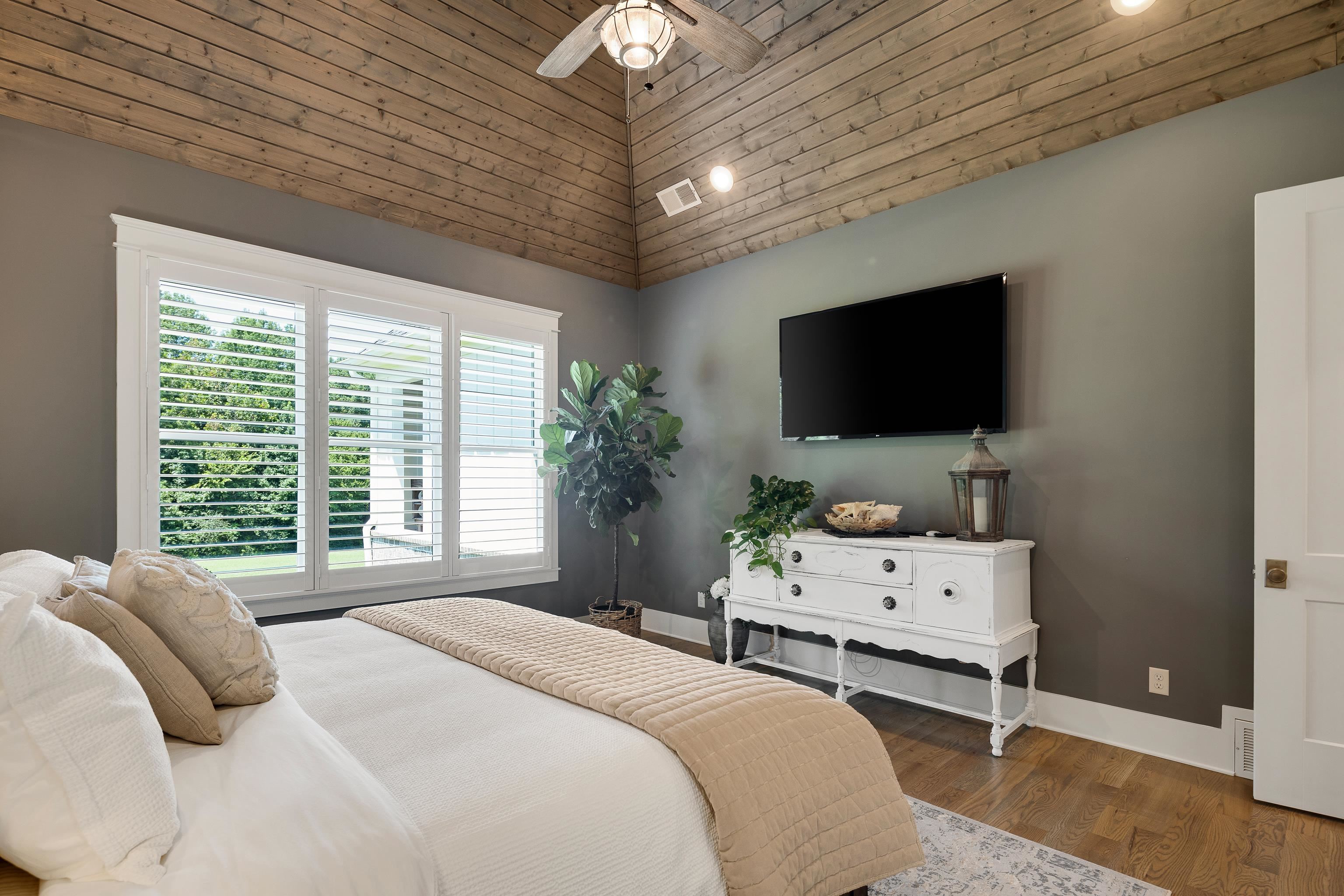 805 Shady Grove Road Williston, TN 38076 - Photo 21 of 40 Vaulted wood-paneled ceiling with ceiling fan, large windows with plantation shutters, wood-finish flooring, and a wall-mounted television