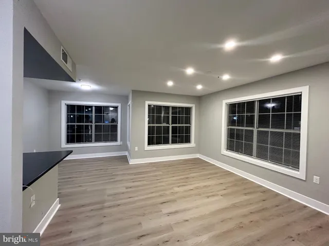a view of an empty room with wooden floor and windows