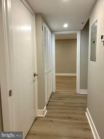 a view of a hallway with wooden floor and a bathroom