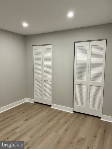 an empty room with wooden floor & closet area