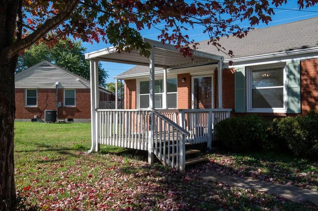 a view of a house with a small yard and a large tree