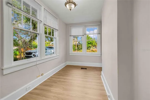 a view of an empty room with a window and wooden floor