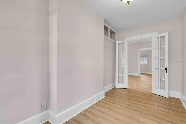 a view of an empty room with wooden floor and a window
