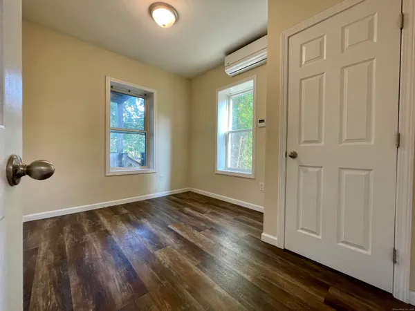 an empty room with wooden floor closet and windows