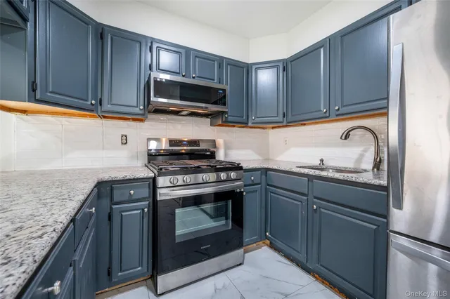 a kitchen with granite countertop wood cabinets stainless steel appliances and a sink