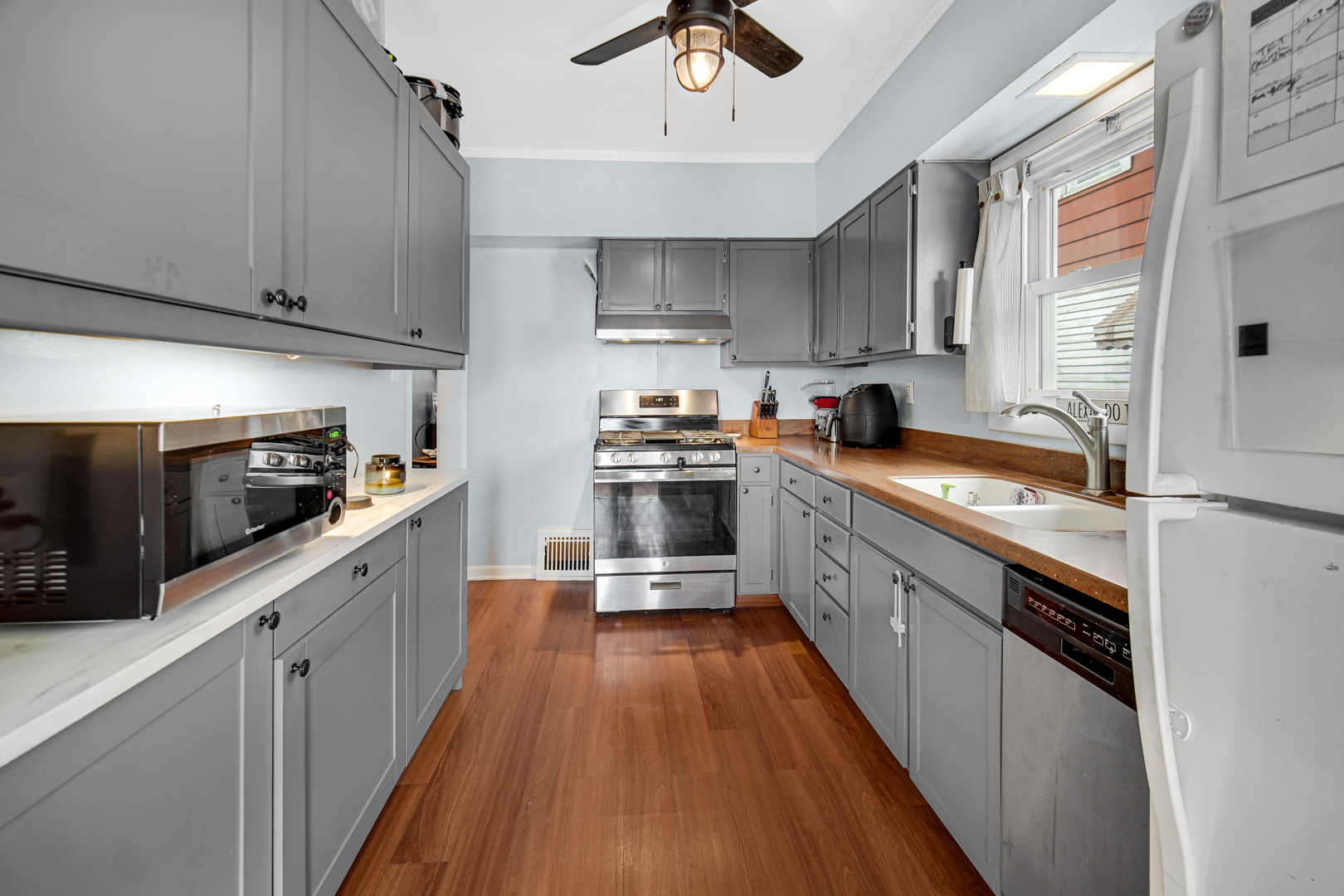 5531 West Grace Street Chicago, IL 60641 - Photo 12 of 22 a kitchen with stainless steel appliances a sink dishwasher a stove top oven a refrigerator with cabinets and wooden floor