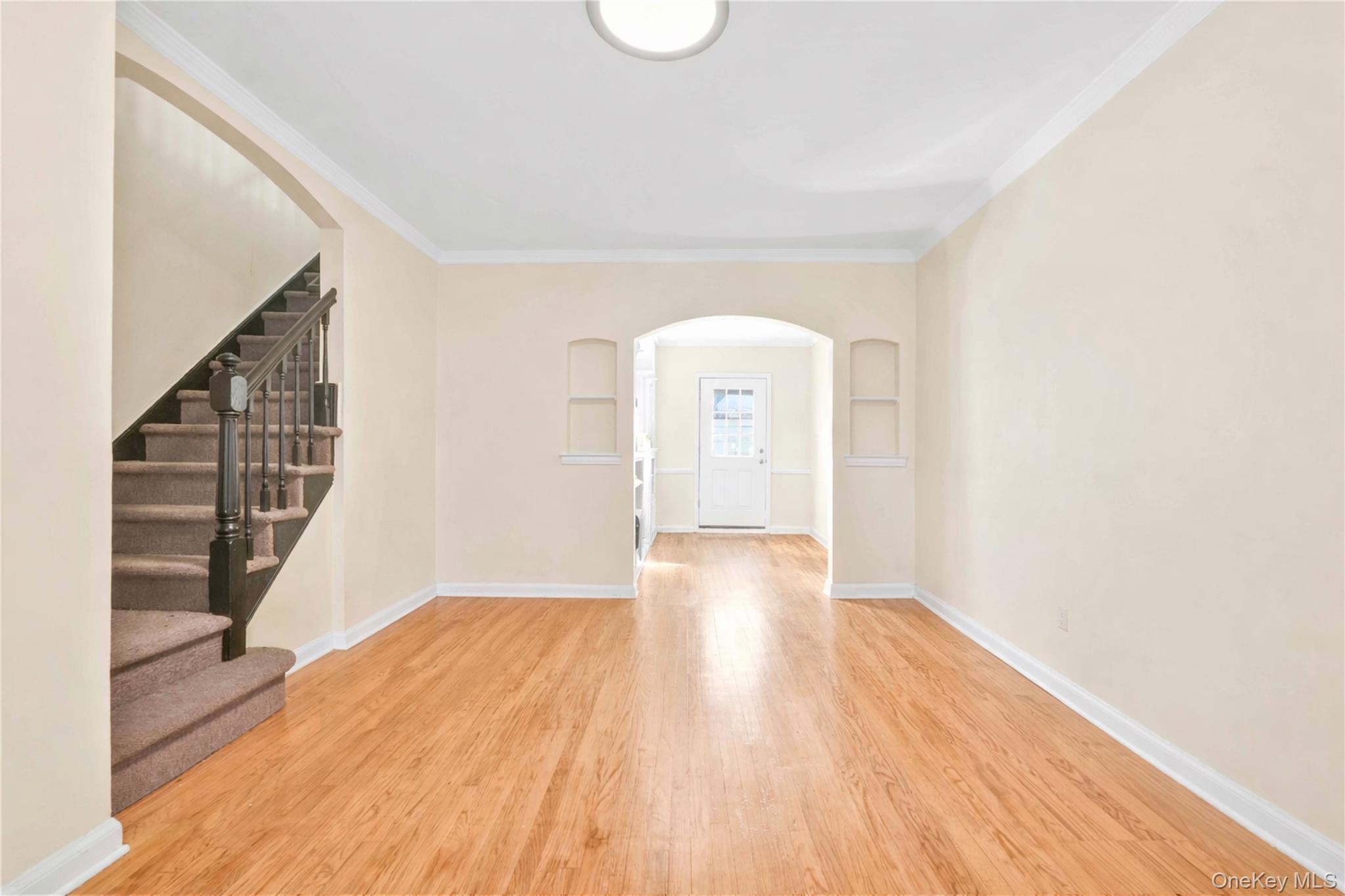 136-76 71st Road Queens, NY 11367 - Photo 12 of 31 a view of an empty room with wooden floor and stairs