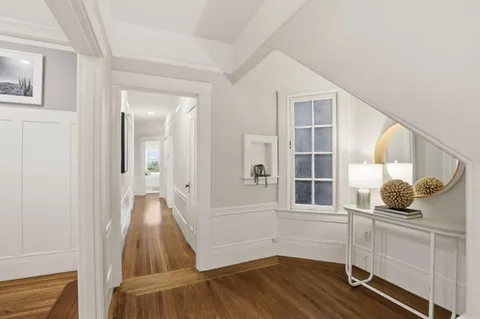 a view of a hallway with wooden floor and staircase