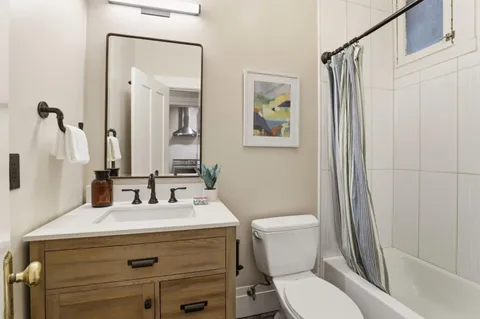 a bathroom with a sink a toilet a mirror and shower