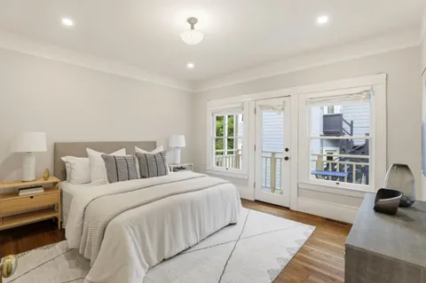 a spacious bedroom with a bed a couch and large window
