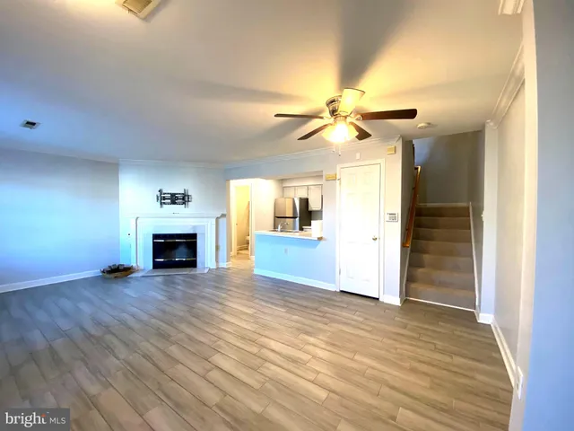 an empty room with wooden floor fireplace and windows