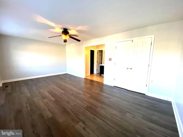 an empty room with wooden floor ceiling fan and windows