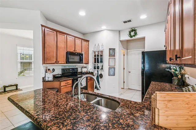 a large kitchen with stainless steel appliances granite countertop a refrigerator oven a sink a dining table and chairs with wooden floor