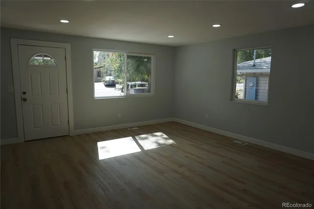 an empty room with wooden floor and windows