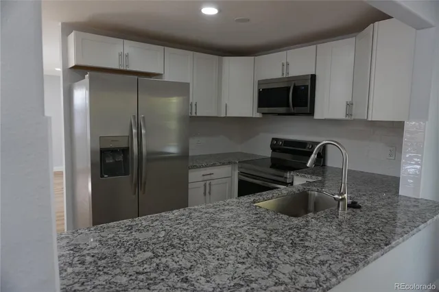 a kitchen with stainless steel appliances granite countertop a refrigerator a stove top oven a sink and dishwasher