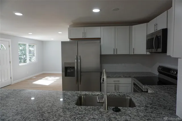 a kitchen with stainless steel appliances granite countertop a refrigerator and a stove top oven