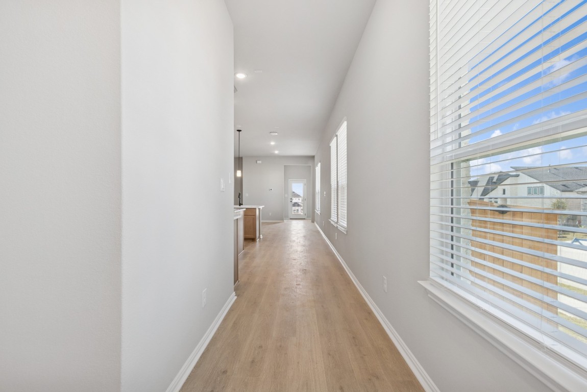 247 Grayson Elm Pass Dripping Springs, TX 78620 - Photo 2 of 39 a view of a hallway with wooden floor and a bathroom