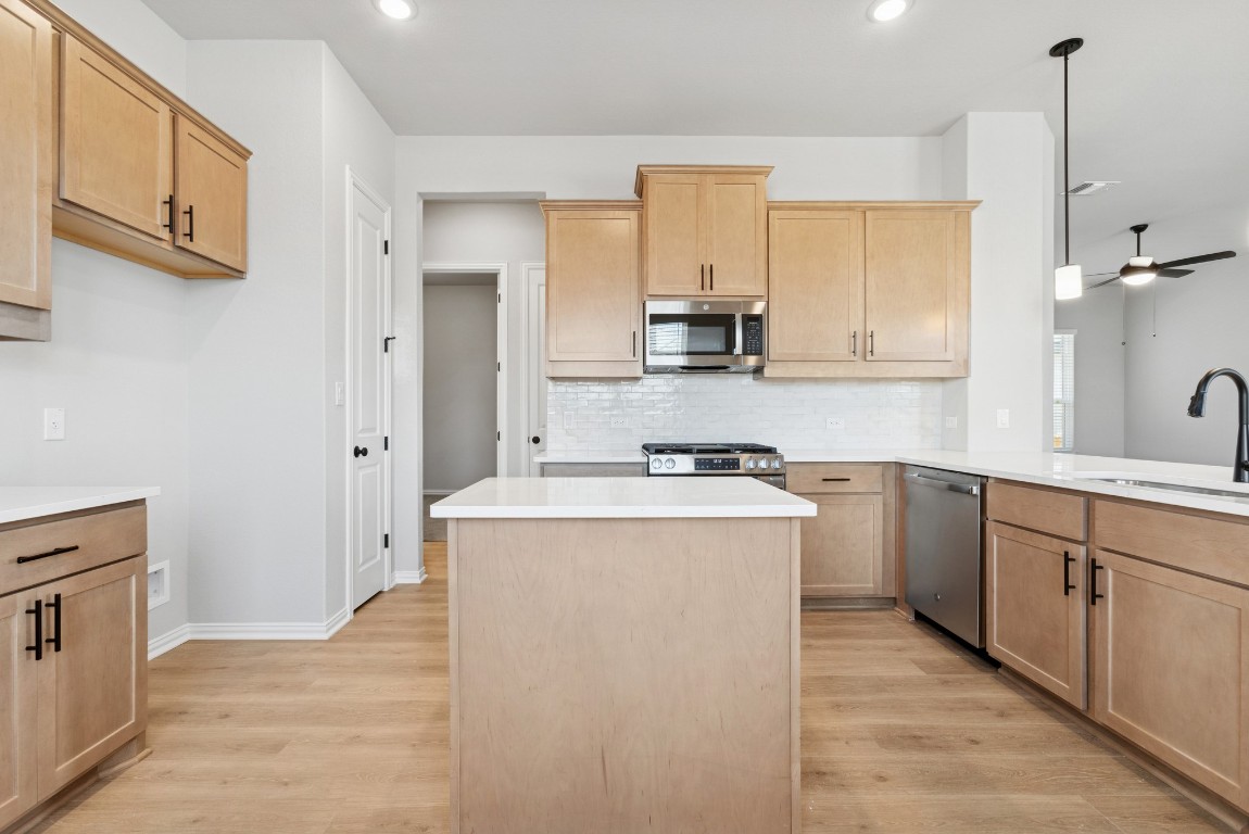 247 Grayson Elm Pass Dripping Springs, TX 78620 - Photo 4 of 39 a kitchen with a stove a sink and a refrigerator