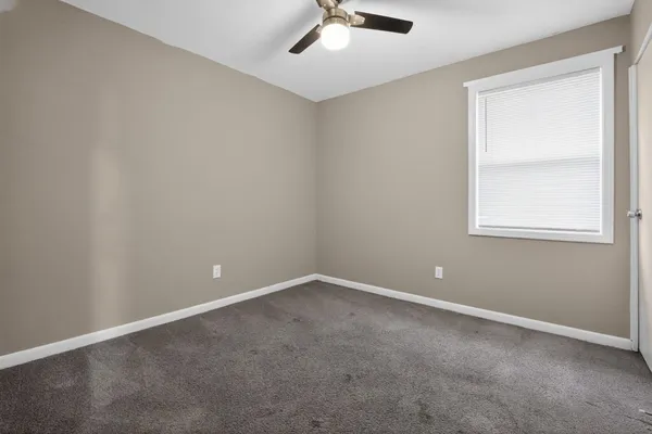 an empty room with a window and a fan