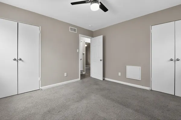 a view of an empty room with chandelier fan