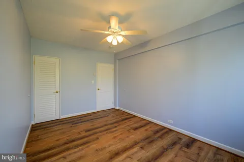 a view of a big room with wooden floor and chandelier fan