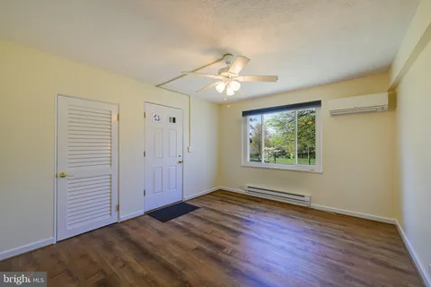 an empty room with wooden floor chandelier fan and windows