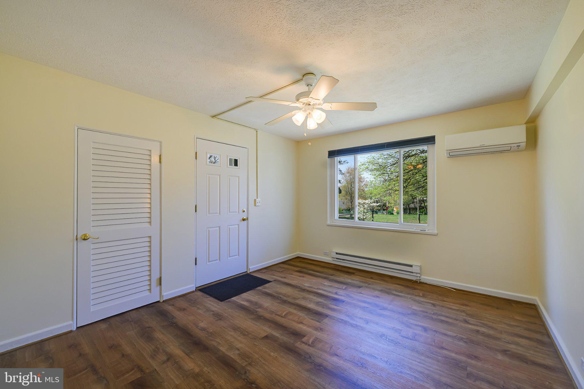 39 Ridge Road Greenbelt, MD 20770 - Photo 4 of 19 an empty room with wooden floor chandelier fan and windows