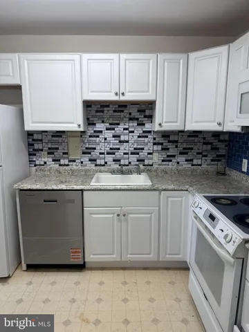 a kitchen with granite countertop white cabinets and white appliances